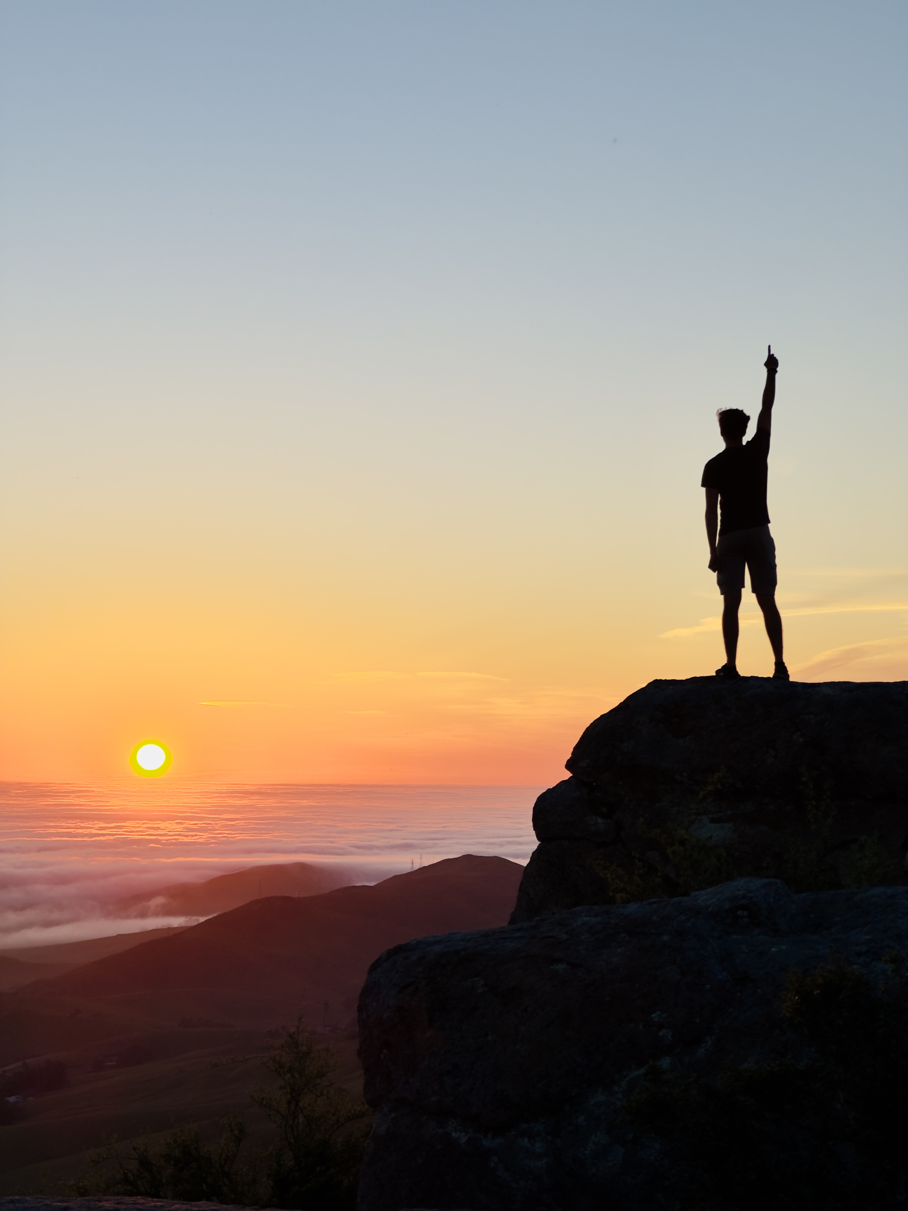 Hunter silhouetted at sunrise summit